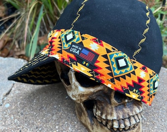 May include: Black canvas work cap with a yellow, orange, red, and blue geometric patterned band. The band has the text "Made in USA" with a small American flag.
