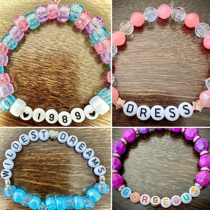May include: Four colorful beaded bracelets with different words spelled out on them. The bracelets are: "Wildest Dreams", "1989", "Dress", and "Gorgeous".