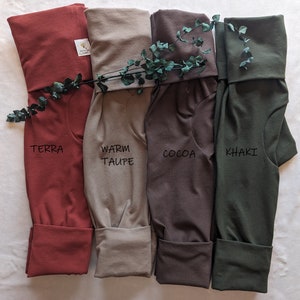 May include: Four pairs of folded pants in different colors: terra, warm taupe, cocoa, and khaki. The pants are made of a soft, comfortable fabric and have a relaxed fit.