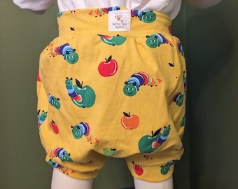 May include: A yellow toddler-sized pair of shorts with a colorful caterpillar and apple print. The shorts have a small tag that reads "The Better Bee Apparel".