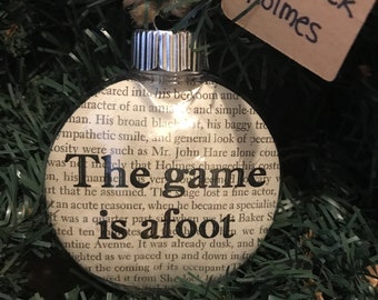 Adorno navideño con cita del libro de Sherlock Holmes; El juego está en marcha