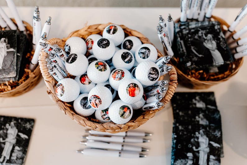 May include: A wicker basket filled with white golf balls, each with a personalized photo. The basket is surrounded by white pens with black ink.