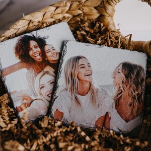 May include: Two sets of coasters with photos printed on them. The coasters are made of slate and are in a wicker basket filled with brown packing paper.