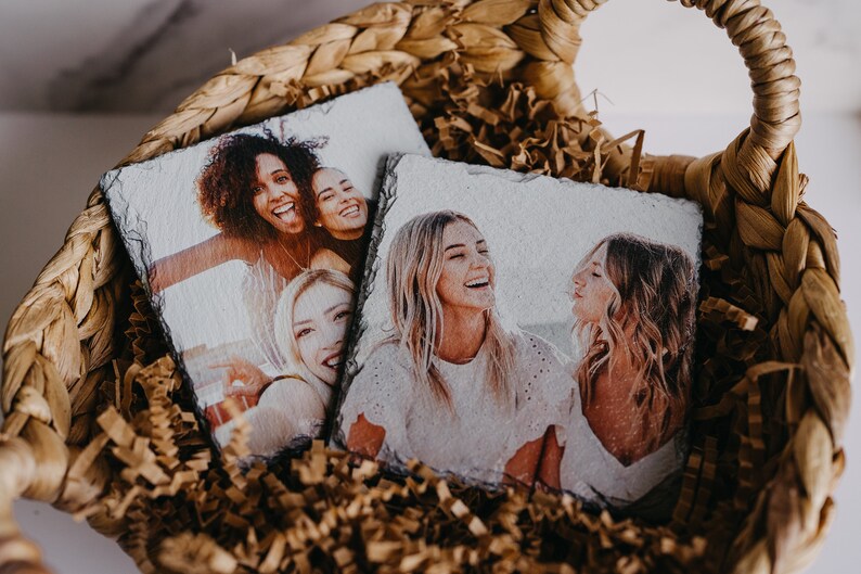 May include: Two sets of coasters with photos printed on them. The coasters are made of slate and are in a wicker basket filled with brown packing paper.