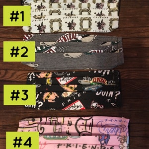 Pode incluir: Quatro máscaras faciais plissadas com vários padrões. A primeira máscara é branca com um padrão repetido do logotipo Friends e detalhes florais. A segunda é cinza com xícaras de café Central Perk. A terceira é preta com personagens de Friends. A quarta é rosa com logotipos Friends.