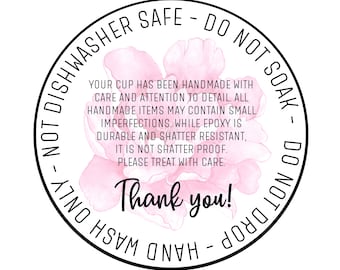May include: A black and white circular sticker with pink floral accents. The sticker reads "Dishwasher Safe - Do Not Soak - Do Not Drop - Hand Wash Only". The text also reads "Your cup has been handmade with care and attention to detail. All handmade items may contain small imperfections. While epoxy is durable and shatter resistant, it is not shatter proof. Please treat with care. Thank you!"