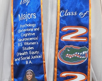 Op de afbeelding: Een blauwe en oranje graduatiessjerp met de tekst "UF Class of 2024" en een alligatorlogo van de University of Florida. De sjerp bevat ook de naam van de afgestudeerde, Rachel Faith Eloy, en een lijst van haar majors: Psychologie (Gedrags- en Cognitieve Neurowetenschappen), B.S. Vrouwenstudies (Gezondheidsequity en sociale rechtvaardigheid), B.A. Een foto van de afgestudeerde is ook inbegrepen.
