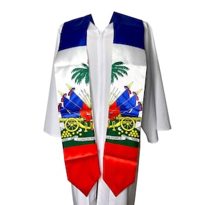 May include: Graduation stole featuring the Haitian flag. The stole is red, white and blue with a green border. The flag depicts a coat of arms with cannons, palm trees, and the text "L'UNION FAIT LA FORCE".