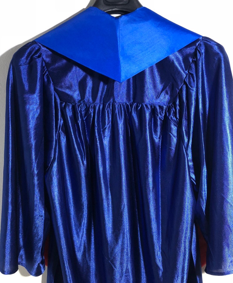 May include: A blue graduation gown with a royal blue collar. The gown is made of a satin-like material.