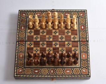 May include: A wooden chess set with inlaid wood details. The chessboard is closed and the pieces are arranged in their starting positions. The chessboard has a dark brown and light brown checkered pattern. The pieces are made of wood and are painted in traditional colors.