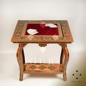 May include: A wooden game table with intricate inlaid designs. The table has a red felt top and a lower shelf. The table is made by Joury Handmade.