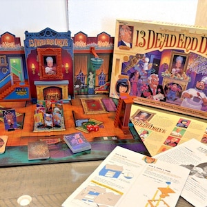 May include: A board game titled "13 Dead End Drive" with a colorful game board, game pieces, and instructions. The game board depicts a house interior with various rooms. The box art features illustrations of characters and the game's title.