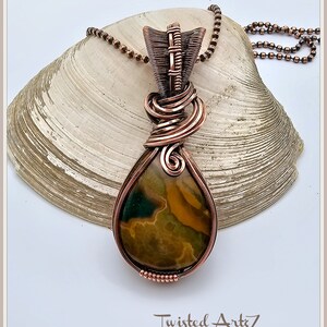 May include: A copper wire wrapped pendant featuring a teardrop shaped green, brown, and yellow agate stone. The pendant is attached to a copper chain.