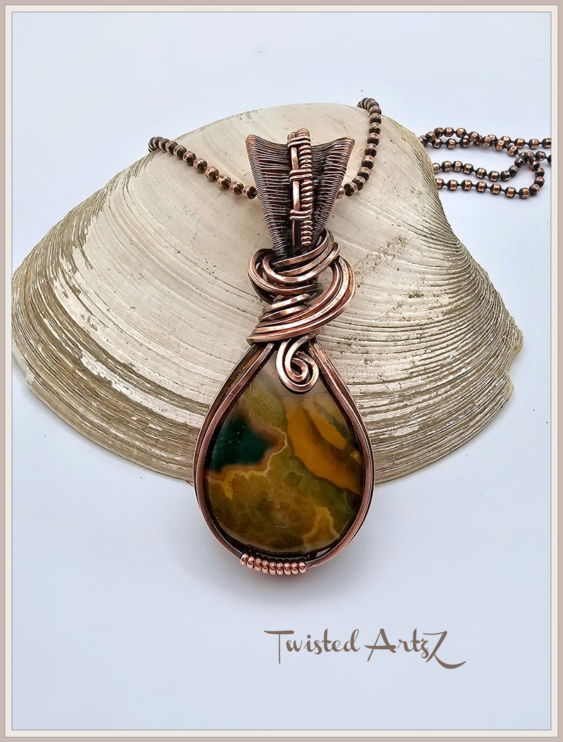 May include: A copper wire wrapped pendant featuring a teardrop shaped green, brown, and yellow agate stone. The pendant is attached to a copper chain.