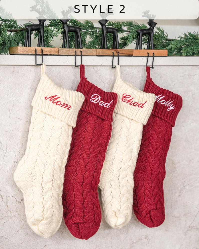 May include: Four knitted Christmas stockings with red and white cable knit patterns. The stockings are hung on a wooden rack with metal hooks. The stockings are personalized with the names "Mom", "Dad", "Chad", and "Molly" in red embroidery.