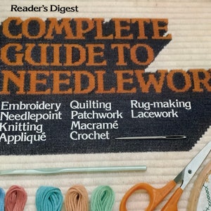 May include: A book titled "Complete Guide to Needlework" by Reader's Digest. The book cover features a black and orange design with the title in large letters. The cover also lists various needlework techniques, including embroidery, quilting, rug-making, needlepoint, patchwork, lacework, knitting, macrame, and applique.