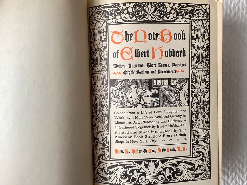 May include: The cover of a book titled "The Note Book of Elbert Hubbard" with a black and white illustration of a printing press and two men working. The book is described as containing "Mottos, Epigrams, Short Essays, Passages, Orphic Sayings and Preachments". The book was "Coined from a Life of Love, Laughter and Work, by a Man Who Achieved Greatly in Literature, Art, Philosophy and Business." The book was "Gathered Together by Elbert Hubbard II" and "Printed and Made into a Book by The American Book-Stratford Press at their Shops in New York City."