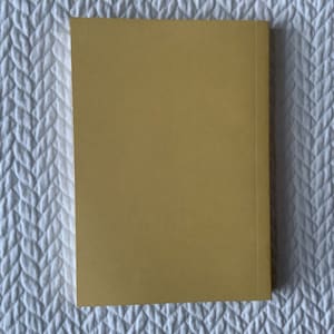 Op de afbeelding: Een effen, geel, hardback boek met een textuur.