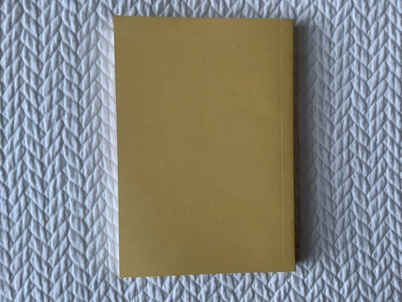 Op de afbeelding: Een effen, geel, hardback boek met een textuur.