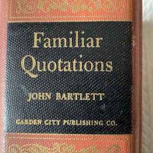 May include: A vintage book titled "Familiar Quotations" by John Bartlett. The book has a black cover with gold lettering and a decorative red and gold spine. Published by Garden City Publishing Co.