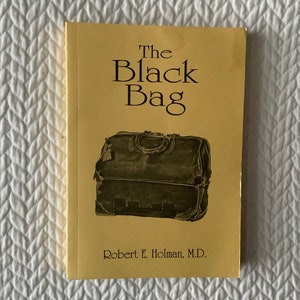 Op de afbeelding: De omslag van een geel boek getiteld "The Black Bag" door Robert E. Holman, M.D. De omslag toont een zwarte leren tas met een versleten en verweerde uitstraling.