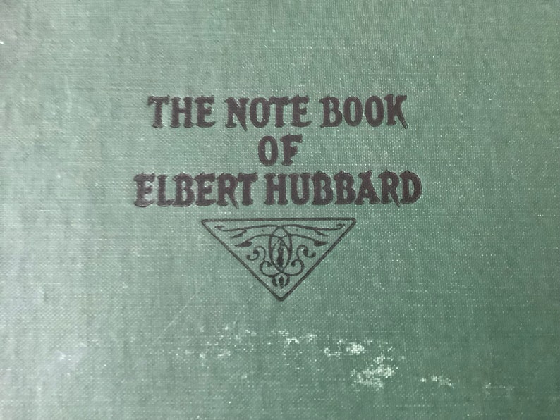 May include: The cover of a green book with the title "The Note Book of Elbert Hubbard" in black lettering.