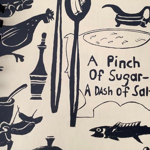 May include: A vintage cookbook with a black and white illustration of a chicken, a fish, a bowl of soup, and a bottle. The title of the book is "A Pinch of Sugar - A Dash of Salt".
