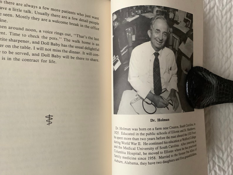 Op de afbeelding: Zwart-witfoto van een dokter die een wit overhemd en een donkere das draagt. Hij houdt een stethoscoop in zijn handen. De foto is afkomstig uit een boek over het leven van een dokter. De tekst onder de foto luidt "Dr. Holman".