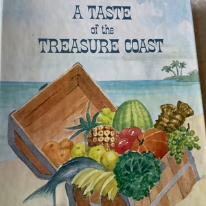 May include: A vintage cookbook titled "A Taste of the Treasure Coast" with a watercolor illustration of a wooden crate filled with fresh produce, including pineapples, oranges, bananas, watermelon, and a fish.