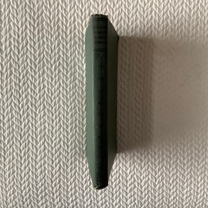 May include: A small, green hardcover book with the title "The Book of the Little  Green  Men" printed on the spine.