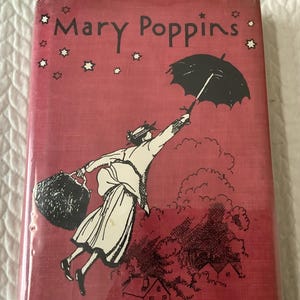 May include: A vintage book cover for "Mary Poppins" in red with a black and white illustration of Mary Poppins flying with an umbrella. The title is in white, with stars scattered around the top.