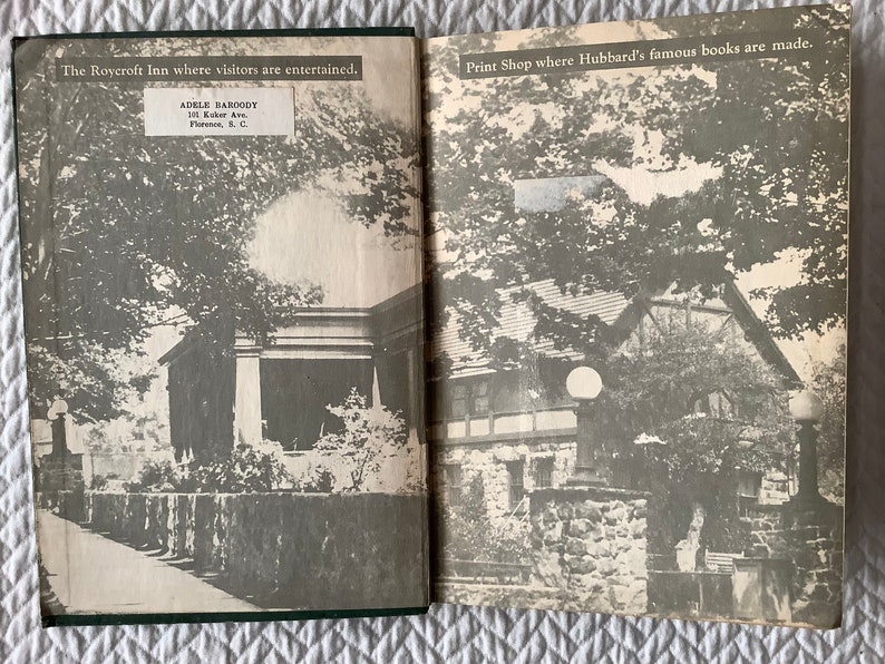 May include: A black and white photo of the Roycroft Inn, a building with a stone wall and a walkway leading to the front door. The text "The Roycroft Inn where visitors are entertained." is printed above the image. The text "ADELE BAHOODY 101 Kuker Av. Florence, S.C." is printed below the image.
