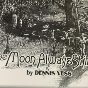 May include: A black and white ink drawing depicting a person sitting by a tree near a stream, with a still in the background. The text reads The Moon Always Shines by DENNIS VESS. The illustration features detailed cross-hatching and line work.