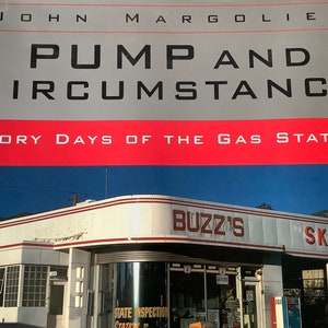 May include: A vintage gas station with a red and white striped awning. The sign reads "Buzz's Skelly".