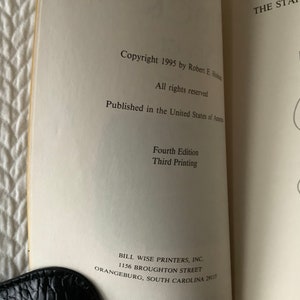 Op de afbeelding: Een boek getiteld "The Staff of Asclepius" met copyrightinformatie, publicatiegegevens en drukgegevens. De omslag van het boek toont een zwart-witte illustratie van een slang die om een staf is gewikkeld.