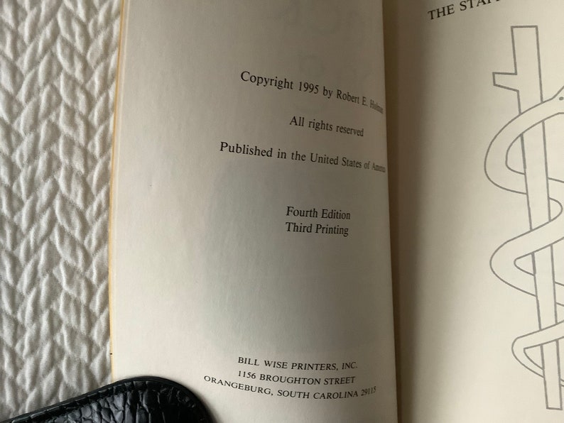 Op de afbeelding: Een boek getiteld "The Staff of Asclepius" met copyrightinformatie, publicatiegegevens en drukgegevens. De omslag van het boek toont een zwart-witte illustratie van een slang die om een staf is gewikkeld.