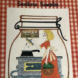 May include: A vintage cookbook titled "Southern Samples" with a red and white gingham cover. The cover features an illustration of a woman in a red dress standing in front of a wood-burning stove. She is holding a basket of green herbs.