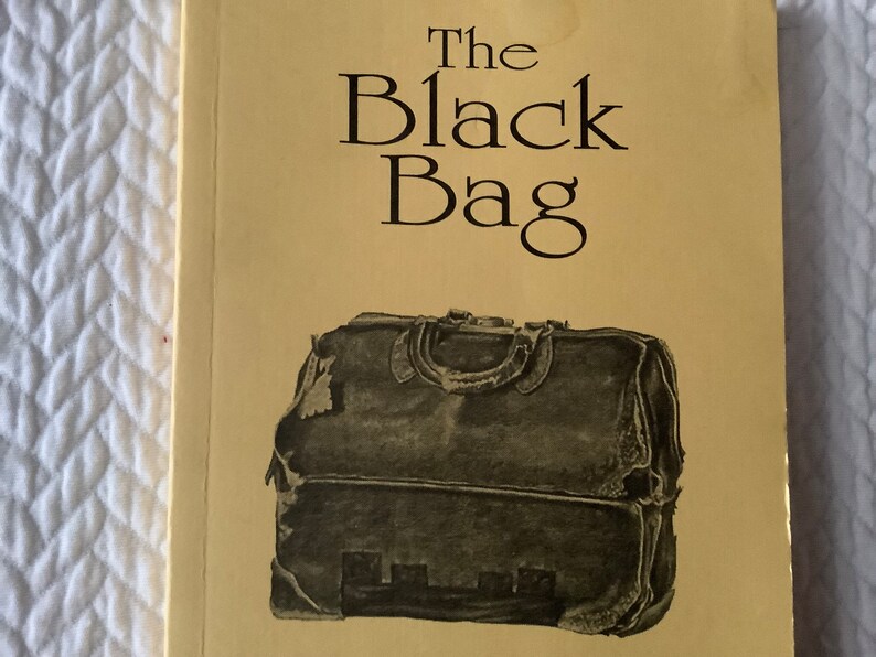 Op de afbeelding: De omslag van een boek getiteld "The Black Bag". De omslag is geel met zwarte tekst en een zwart-witte illustratie van een versleten leren tas.