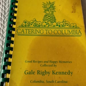 May include: A white ceramic mug with a black handle and the text "But First, Coffee" in a black, handwritten-style font. The mug is on a white surface.