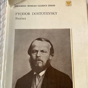 May include: A black and white photo of Fyodor Dostoevsky, a Russian author, on the cover of a book titled "Fyodor Dostoevsky Stories". The book is part of the "Progress - Russian Classics Series".