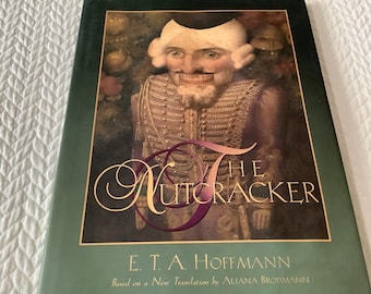 May include: The Nutcracker by E.T.A. Hoffmann, based on a new translation by Aliana Brofmann. The cover features a detailed illustration of the Nutcracker, a wooden toy soldier with a large, toothy grin, wearing a red and gold uniform.