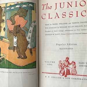 May include: An open book with illustrations and text. The left page features a colorful illustration of three bears in a domestic setting. The right page displays the title "The Junior Classics" in red, along with author and publisher information.