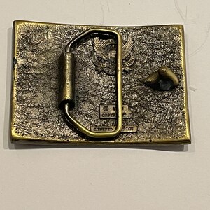 May include: A brass belt buckle featuring an eagle design and the text "Copyright 1981 Limited Edition".