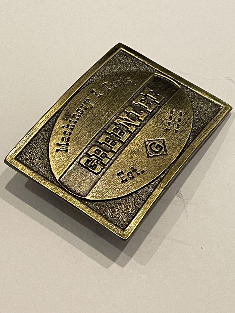 May include: A gold-toned metal belt buckle with the text "G.E.F.E.N.L.A.T.E. Est. 1955" and "Machine W. Tools" engraved on it.