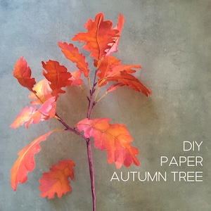 May include: DIY Paper Autumn Tree craft project featuring a branch of orange paper leaves against a grey background. The text "DIY Paper Autumn Tree" is written in white letters on the bottom right of the image.