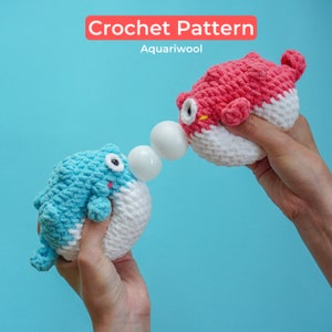 May include: Two crocheted pufferfish toys, one blue and one red, with white bellies, are held by hands. The toys are facing each other and have white balls between them. The background is a light blue color. Crochet Pattern Aquariwool.
