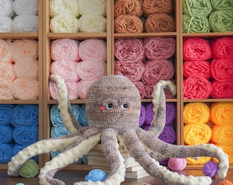 May include: A crocheted octopus toy with brown and white yarn. The octopus is sitting on a stack of books with balls of yarn in various colors in the background. The text "Aquariwool Crochet" is visible at the bottom of the image.
