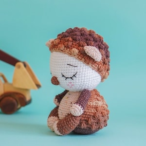 Puede incluir: Un juguete de erizo de crochet hecho con hilo marrón y blanco. El juguete tiene los ojos cerrados y una nariz marrón.