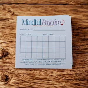 May include: A stack of light blue "Mindful Practice" metronome charting sheets. The sheets have a grid for tracking tempo and a musical note graphic. Text on the sheet includes "3 Times Rule" and "Practice Makes Progress!"