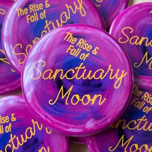 May include: Several circular buttons in shades of purple, blue, and pink, with the text "The Rise & Fall of Sanctuary Moon" in gold script. The buttons have a swirling pattern and are arranged in a slightly overlapping manner, creating a visually appealing display.